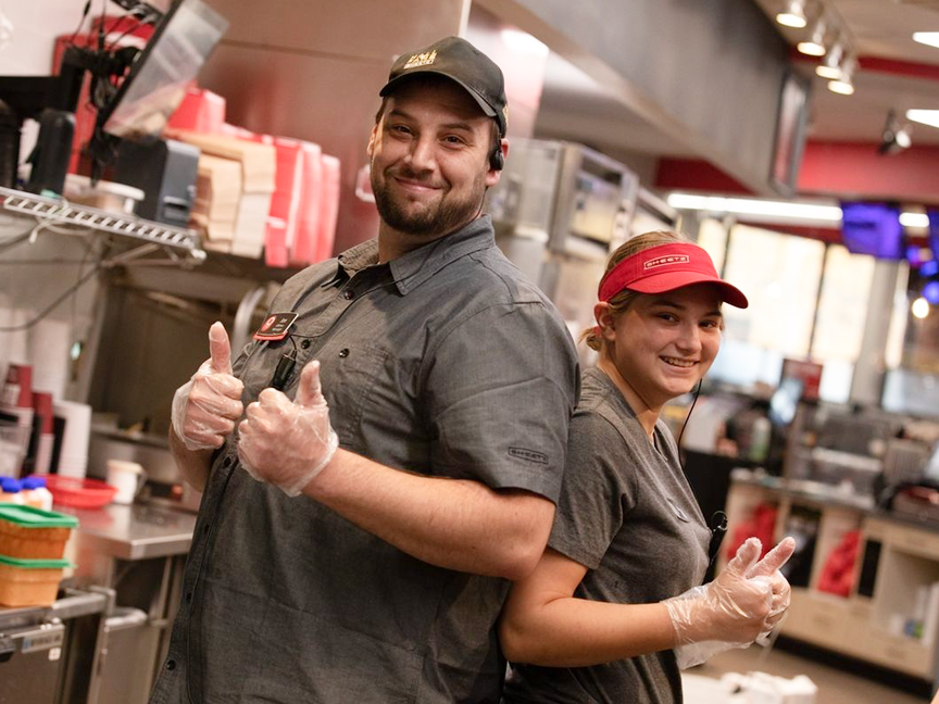 Two employees smiling and giving thumbs-up