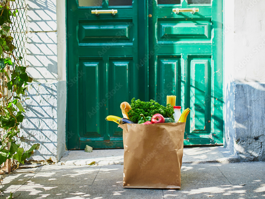 a bag of groceries on a porch in front of a green door