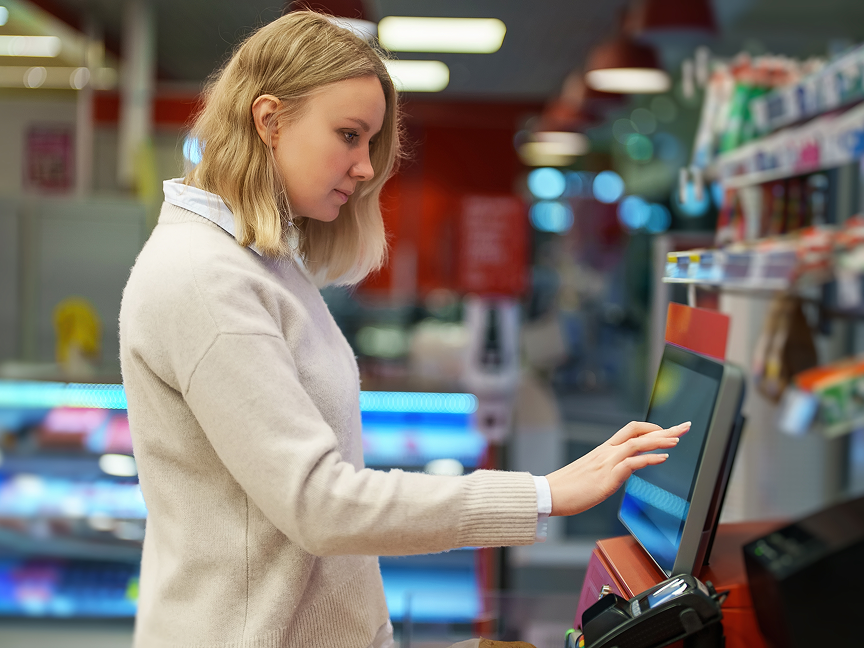 A woman using the self-checkout counter at a grocery store