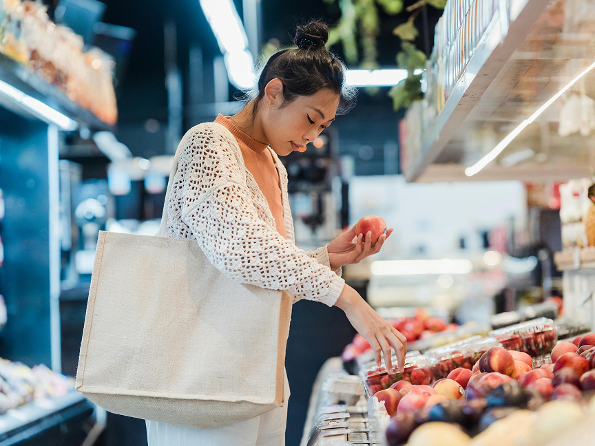 A customer sorts through peaches in a grocery store