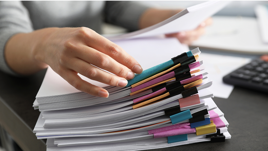 A person sorts through a stack of marked papers 